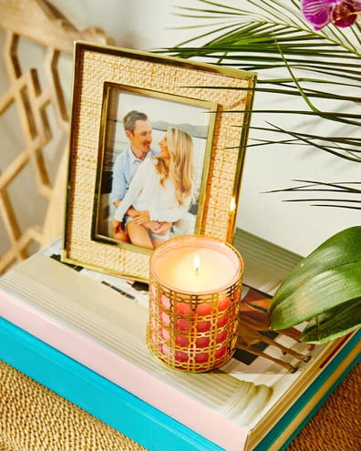 gold frame with gold and pink candle on top of books