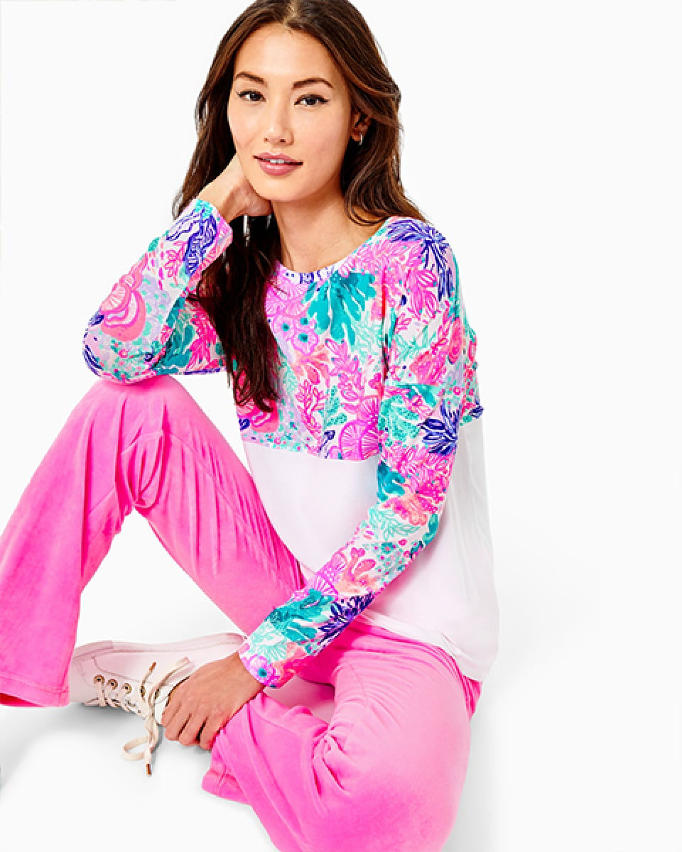 woman sitting wearing pink flare pants and a finn top
