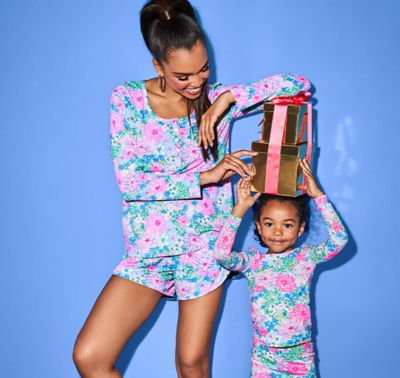 woman smiling wearing matching pajamas with daughter