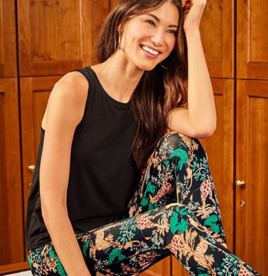 Woman wearing a black active tank top and black and green animal printed leggings