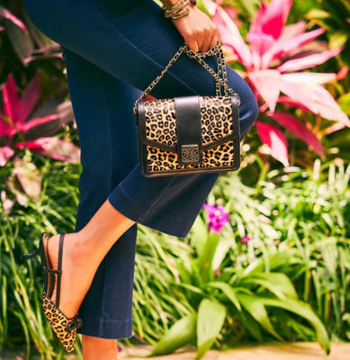 Woman holding a cheetah printed crossboday bag and matching kitten heels