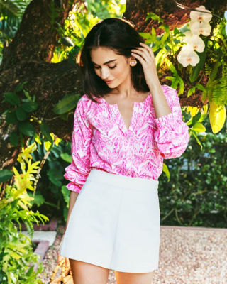 Woman wearing a pink printed top and white shorts