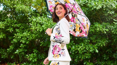 Woman wearing a white printed blazer and holding an umbrella