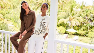 Woman wearing a brown sweatshirt and sweatpants and another woman wearing a cream sweatshirt and sweatpants