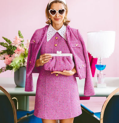 Woman wearing a pink boucle romper with a matching jacket and purse