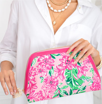 Close up of women wearing a white shirt and holding a pink and green floral printed clutch