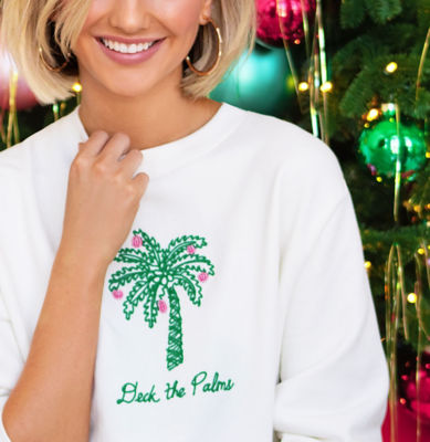 Woman wearing a white sweatshirt with a green palm tree graphic