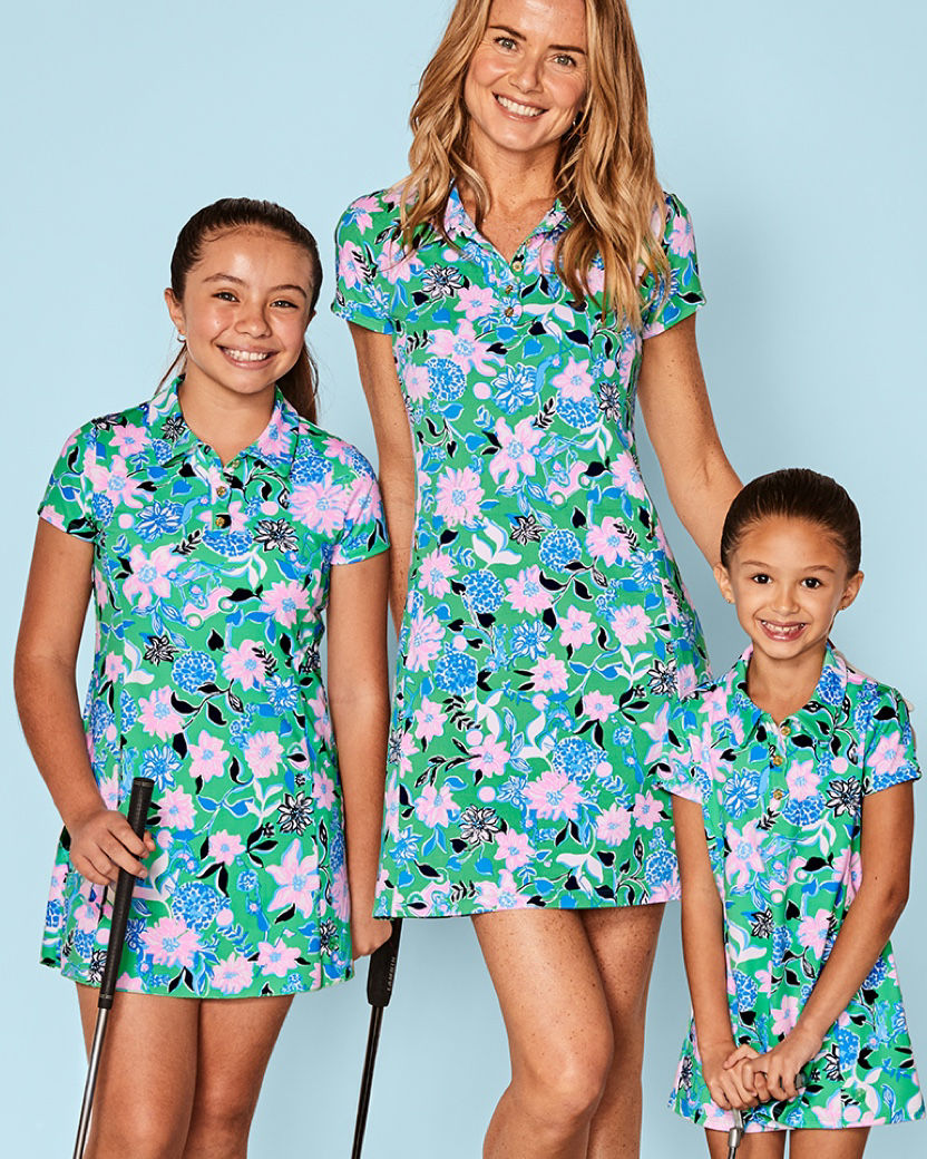Woman and two girls wearing matching green floral printed golf dresses