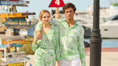 Woman and man wearing green and white printed outfits