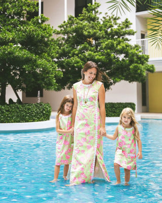 Family wearing matching pink and green printed dresses