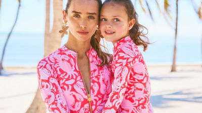 Woman and little girl wearing matching pink and red printed swimwear
