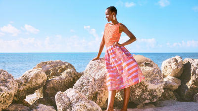 Woman wearing an orange cropped top and an orange and purple printed midi skirt